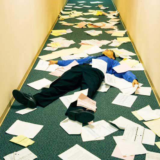 Man lying down in a hallway surrounded by papers