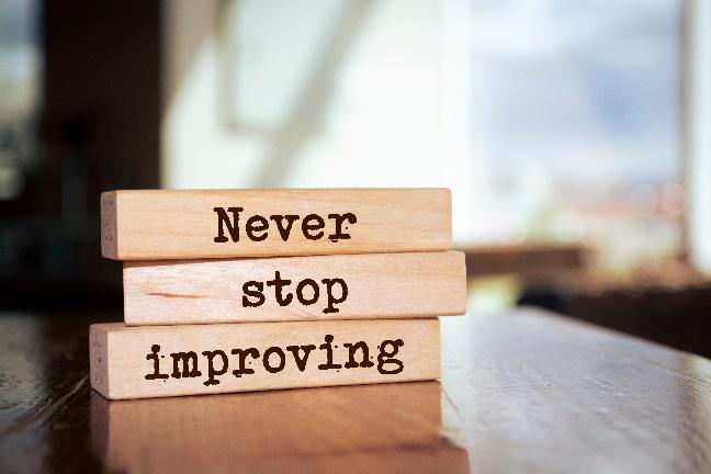 3 wood blocks stacked on a table, with the words 'Never stop improving'